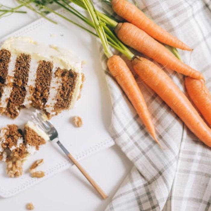 Carrot cake next to a bunch of carrots.